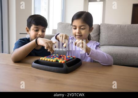 Positive süße indische Bruder- und Schwester-Kinder, die Brettspiel spielen Stockfoto