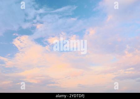Weiche pastellfarbene Wolken ziehen am frühen Morgen oder am späten Nachmittag in einer ruhigen Landschaft über einen hellblauen Himmel Stockfoto