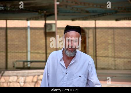 Buchara, Usbekistan; 19. September 2024: Nahaufnahme eines in weiß gekleideten usbekischen Mannes, der den traditionellen Tyubeteika-Hut in Buchara, Usbekistan, trägt. Stockfoto