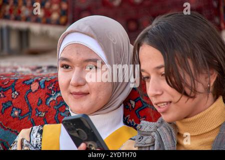 Chiwa, Usbekistan; 21. September 2024: Zwei junge usbekische Frauen schlendern durch die malerischen Straßen von Chiwa, Usbekistan. Stockfoto