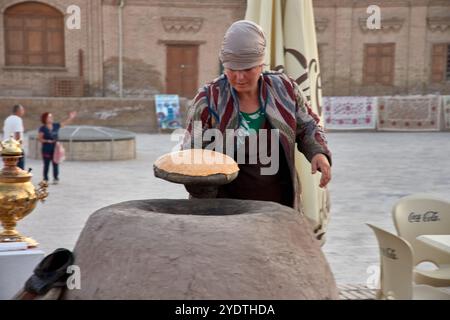 Chiwa, Usbekistan; 21. September 2024: Eine usbekische Frau, die traditionelles Brot auf dem historischen Hauptplatz von Chiwa, Usbekistan, backt. Stockfoto