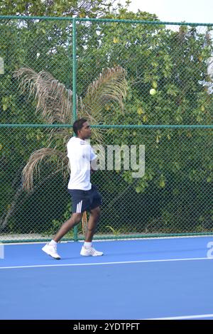 Randheli, Malediven - 24. Februar 2014: Ein asiatischer Indianer spielt Tennis auf einem tropisch blauen Tennisplatz. Stockfoto