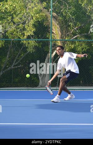 Randheli, Malediven - 24. Februar 2014: Ein asiatischer Indianer spielt Tennis auf einem tropisch blauen Tennisplatz. Stockfoto