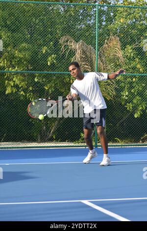 Randheli, Malediven - 24. Februar 2014: Ein asiatischer Indianer spielt Tennis auf einem tropisch blauen Tennisplatz. Stockfoto
