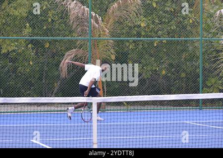 Randheli, Malediven - 24. Februar 2014: Ein asiatischer Indianer spielt Tennis auf einem tropisch blauen Tennisplatz. Stockfoto