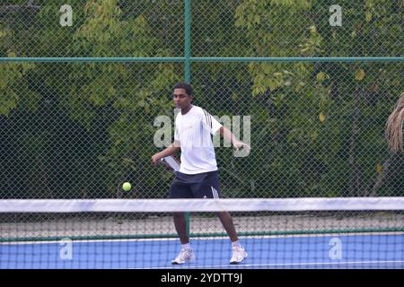 Randheli, Malediven - 24. Februar 2014: Ein asiatischer Indianer spielt Tennis auf einem tropisch blauen Tennisplatz. Stockfoto