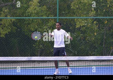 Randheli, Malediven - 24. Februar 2014: Ein asiatischer Indianer spielt Tennis auf einem tropisch blauen Tennisplatz. Stockfoto