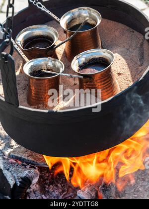 türkischer Kaffee in heißem Sand über offenem Feuer kochen Stockfoto