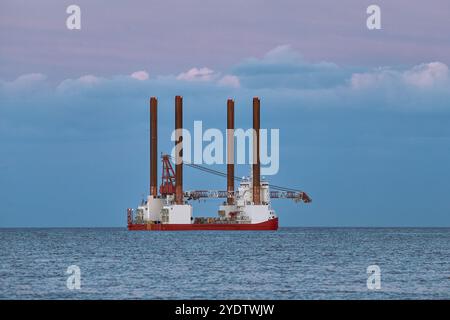 Windturbinen-Installationsschiff im Meer mit wunderschönem, farbenfrohen Himmel aufbocken. Stockfoto