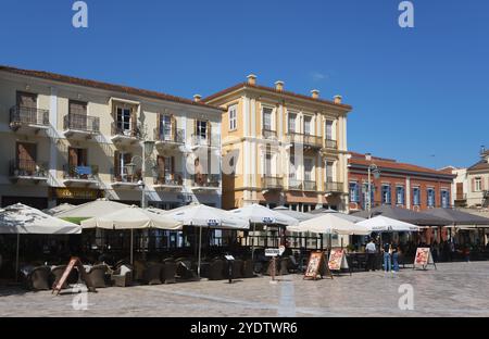 Blick auf die historische europäische Stadt mit Cafés und Sonnenschirmen vor farbenfrohen Gebäuden, Syntagma-Platz, Nafplio, Nafplio, Nafplio, Nafplio, Argolis, Peloponnes Stockfoto