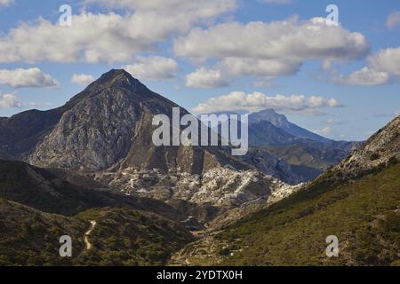 Berglandschaft mit felsigen Gipfeln unter leicht bewölktem Himmel, umgeben von grünem Tal, farbenfrohen Bergdorf, Morgenlicht, Olymbos, Karpa Stockfoto