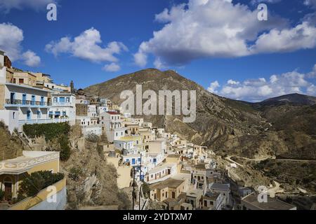 Dorf auf einem Berghang unter einem hellblauen Himmel mit Wolken, buntes Bergdorf, Morgenlicht, Olymbos, Karpathos, Dodekanesisch, Griechische Insel Stockfoto