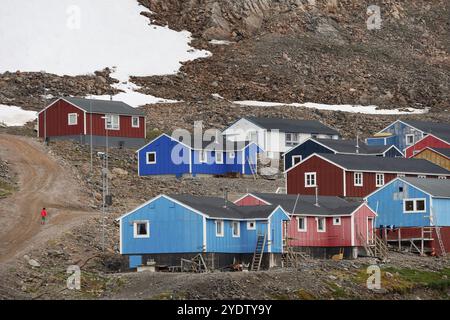 Schotterstraße und farbenfrohe Holzhäuser an einem Hang mit Schneeresten, Inuit Siedlung Ittoqqortoormiit, Scoresbysund oder Scoresby Sund oder Grönland Stockfoto