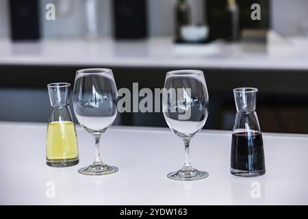 Zwei kleine Dekanter oder Mini-Flaschen gefüllt mit Rot neben Weißweinen und leeren Gläsern, Weinverkostung Stemware Portodekanter Zubehör Stockfoto