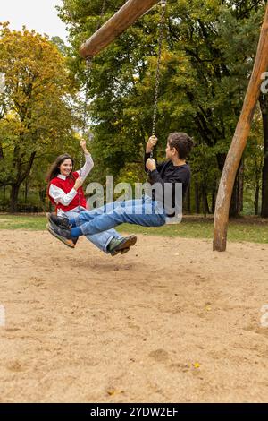 Mutter und Sohn haben Spaß im Stadtpark, verbringen Zeit miteinander, reiten auf den Schaukeln Stockfoto