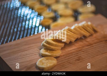 Frische Bananenscheiben liegen auf einem hölzernen Schneidebrett und können als Zutaten verwendet werden. Die Bananenscheiben sind in einer Reihe angeordnet und laden zum Sternen ein Stockfoto