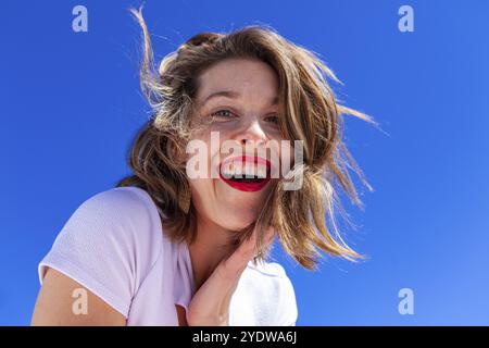 Eine Nahaufnahme von einem schönen kaukasischen Dame, mit gewellten braunen Haar, wie sie lacht und berührt die Seite ihr Gesicht. Glücklich und sorgenfrei weiblichen portrai Stockfoto