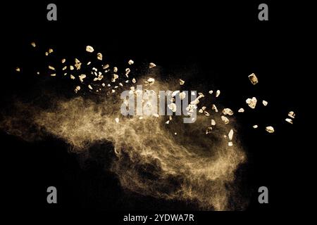 Zersplitterter Steinschutt, der mit braunem Pulver auf schwarzem Hintergrund explodiert Stockfoto