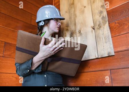 Prüfung der Luftqualität in Innenräumen. Weibliche Inspektorin, die während einer Hausinspektion vor dem Kauf nach Schimmelpilzen oder Pilzproblemen an Holzwänden sucht Stockfoto