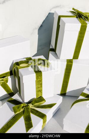 Gestapelte Geschenkboxen mit grünen Samtbändern auf einer glitzernden Oberfläche Stockfoto