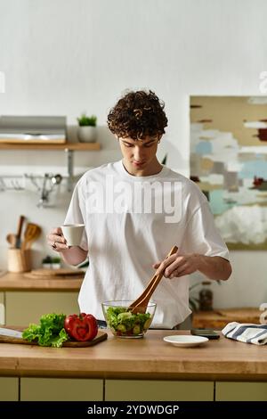 Ein gutaussehender junger Mann mischt einen lebendigen Salat und genießt einen gesunden Lebensstil in seiner eleganten Küche. Stockfoto