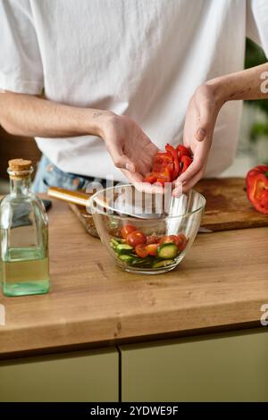 Ein junger Mann, der geschickt einen lebendigen Salat in einer modernen Küche zubereitet und ein gesundes Leben einnimmt. Stockfoto