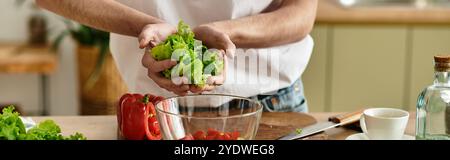 Ein junger Mann mit lockigen Haaren macht gekonnt einen bunten Salat in seiner modernen Küche, der die Gesundheit betont. Stockfoto