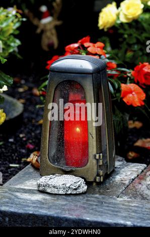 Grab Licht mit brennenden Kerze auf einem Grab mit Blumen an einem Herbstabend Stockfoto