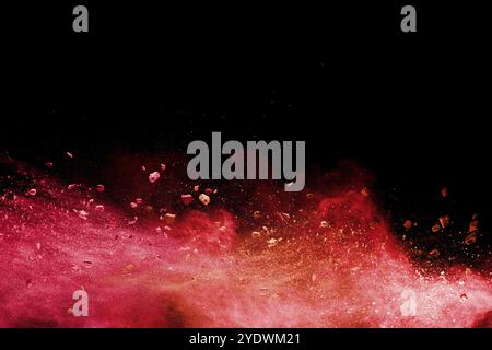 Zersplitterte Steinreste, die mit orangefarbenem Pulverspritzer vor schwarzem Hintergrund explodieren Stockfoto