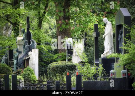 Historische Gräber mit Engeln und Figuren Jesu in hoffnungsvoller, freundlicher Frühlingsatmosphäre auf dem historischen Melaten-Friedhof in Köln Stockfoto