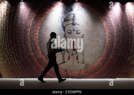 Neu Delhi, Indien. Oktober 2024. Ein Kellner läuft vor einer Wand mit indischen Bildern und Mustern bei einer Veranstaltung. Quelle: Sebastian Christoph Gollnow/dpa/Alamy Live News Stockfoto