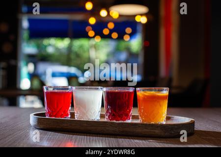 Vier farbenfrohe Aufnahmen von alkoholischen Getränken auf Holztablett Stockfoto