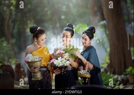 Drei lächelnde junge Frau in traditioneller laotischer Kleidung mit Schüsseln frischer Blumen, Laos Stockfoto