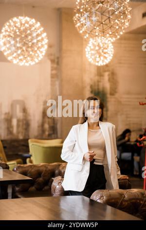 Elegante Frau im schicken Café, umgeben von moderner Beleuchtung. Stockfoto