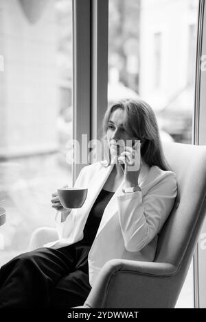 Geschäftsfrau in einem Café, die telefoniert, während sie Kaffee genießt. Stockfoto