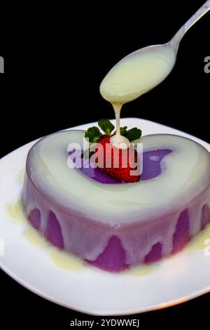 Nahaufnahme eines herzförmigen Erdbeerkuchens mit Vanillesauce Stockfoto