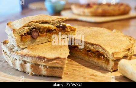 Gebackener Zwiebelkuchen gefüllt mit Oliven, gemischten Zwiebeln und grünen Zwiebeln mit goldbrauner Kruste auf einem verbrannten Holzbrett. Focaccia con cipolle Stockfoto