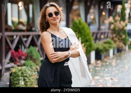 Stilvolle Frau in Sonnenbrille strahlt Vertrauen in die herbstliche Umgebung aus. Stockfoto