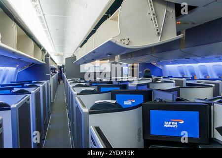 Innenansicht einer modernen Business-Class-Kabine der British Airways Boeing 777 mit geräumigen Sitzplätzen und blauer Umgebungsbeleuchtung Stockfoto