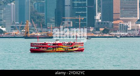 Hongkong, China - 27. April 2009: Eine farbenfrohe Fähre fährt über den Victoria Harbour mit den Wolkenkratzern der Stadt im Hintergrund. Stockfoto