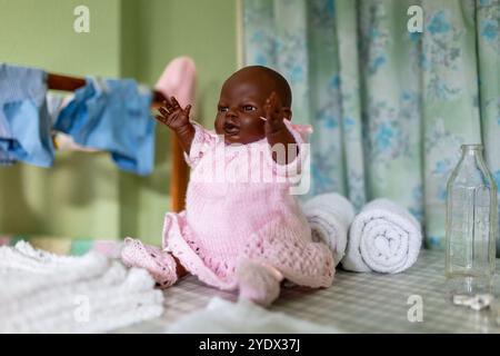 Niedliche schwarze Babypuppe in rosa Kleid an einem Wäschetag Stockfoto