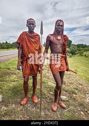 Februar 2024. Masai Mara, Nationalpark. Kenia: Maasai bemannt sich in traditioneller bunter Kleidung auf der Straße in der Nähe des Maasai Mara National Reserve Kenia Stockfoto