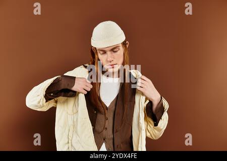 Ein Teenager mit auffälligen roten Haaren posiert selbstbewusst und stellt seine modische Kleidung in einem eleganten Studio zur Schau. Stockfoto