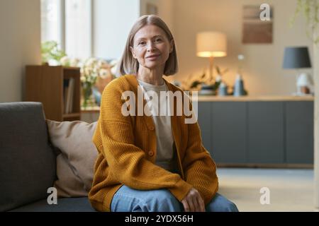 Eine ältere Frau trägt zu Hause eine Strickjacke Stockfoto