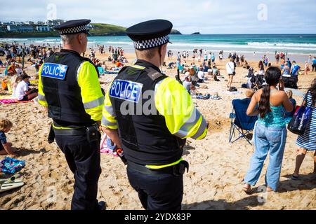 Zwei Beamte der Polizei von Devon & Cornwall patrouillieren unter Urlaubern, die sich am Fistral Beach in Newquay in Cornwall in Th amüsieren Stockfoto