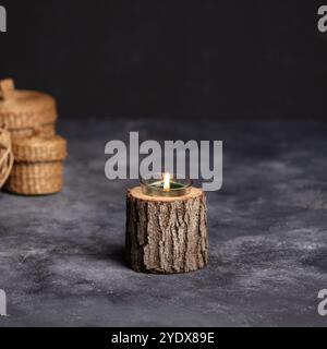 Rustikaler Kerzenhalter mit Tannenzapfen auf Holzscheibe - gemütliche Wohnkultur für Herbst und Winter* Stockfoto