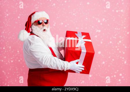 Profil Seite Foto erstaunt Fett weihnachtsmann halten großes Geschenk Box bekommt er Weihnachten nacht Geist fröhliche Event tragen Kopfbedeckung Strapshalter insgesamt Stockfoto