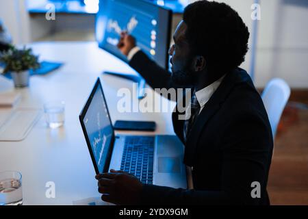 Afrikanischer Trader, der Börsenanalysen im Hedgefonds-Büro erstellt - Unternehmens- und Finanzkonzept - Fokus auf afrikanisches Mann-Ohr Stockfoto