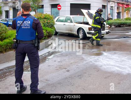 Der weiße 1980er Bentley brannte den Motorraum aus, die Motorhaube war offen und die Polizei und die Feuerwehr waren in einer Straße im Stadtzentrum von Madrid, Spanien Stockfoto