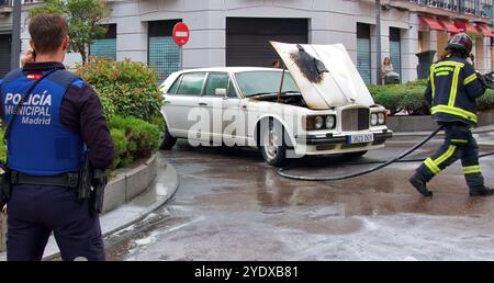 Der weiße 1980er Bentley brannte den Motorraum aus, die Motorhaube war offen und die Polizei und die Feuerwehr waren in einer Straße im Stadtzentrum von Madrid, Spanien Stockfoto